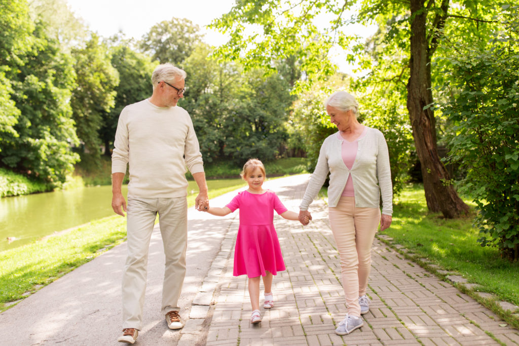 senior grandparents and granddaughter at park